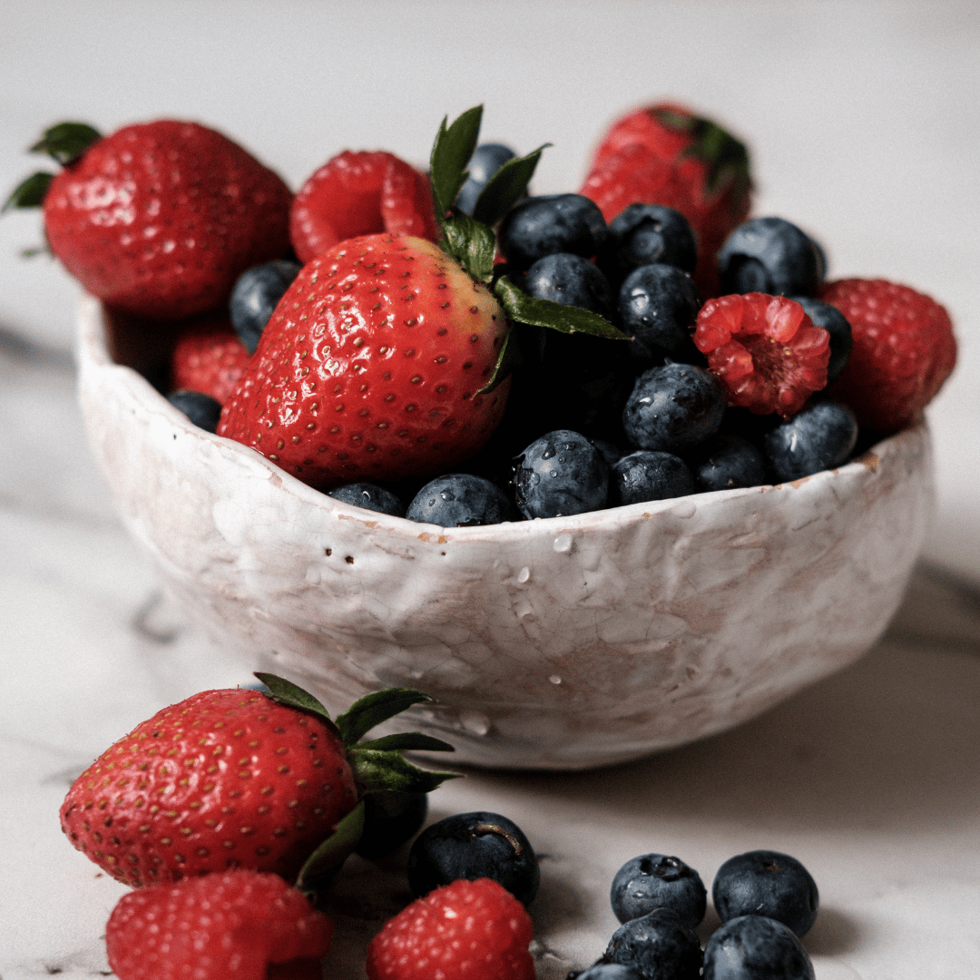 Strawberries, blueberries and raspberries in a white bowl